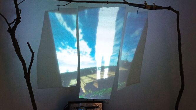 videostill showing installation with image of sky and white scheme of a person